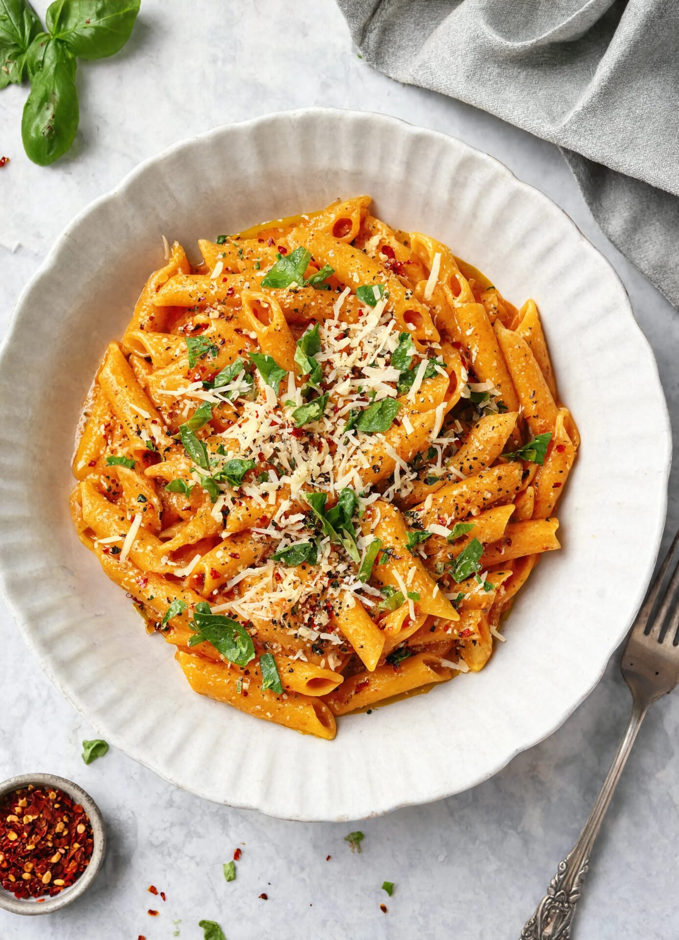 Creamy Tomato Pasta Ingredients 12 oz penne or rigatoni 1 can of crushed tomatoes, 28 oz 5 cloves garlic, thinly sliced 3 tablespoons olive oil 1 teaspoon red pepper flakes 1 teaspoon sugar Salt and black pepper to taste 1/3 cup heavy cream 1/2 cup fresh basil, torn 1/2 cup reserved pasta cooking water Freshly grated Parmesan for serving Instructions Bring a large pot of well-salted water to a boil. Cook the pasta until just al dente according to the package. Before draining scoop out half a cup of the pasta water and set it aside. While the pasta cooks, heat the olive oil in a large wide skillet over medium heat. Add the garlic and red pepper flakes and cook gently for about 2 minutes, stirring often, until the garlic is pale golden. Pour in the crushed tomatoes. Add the sugar, salt, and pepper. Simmer for 8 minutes, stirring occasionally, until the sauce thickens and deepens in color. Stir in the heavy cream and cook for 2 more minutes. Add the drained pasta to the sauce and toss vigorously. Add the reserved pasta water a splash at a time and keep tossing until the sauce is glossy and clings to every piece. Scatter torn basil over the top and serve with Parmesan.